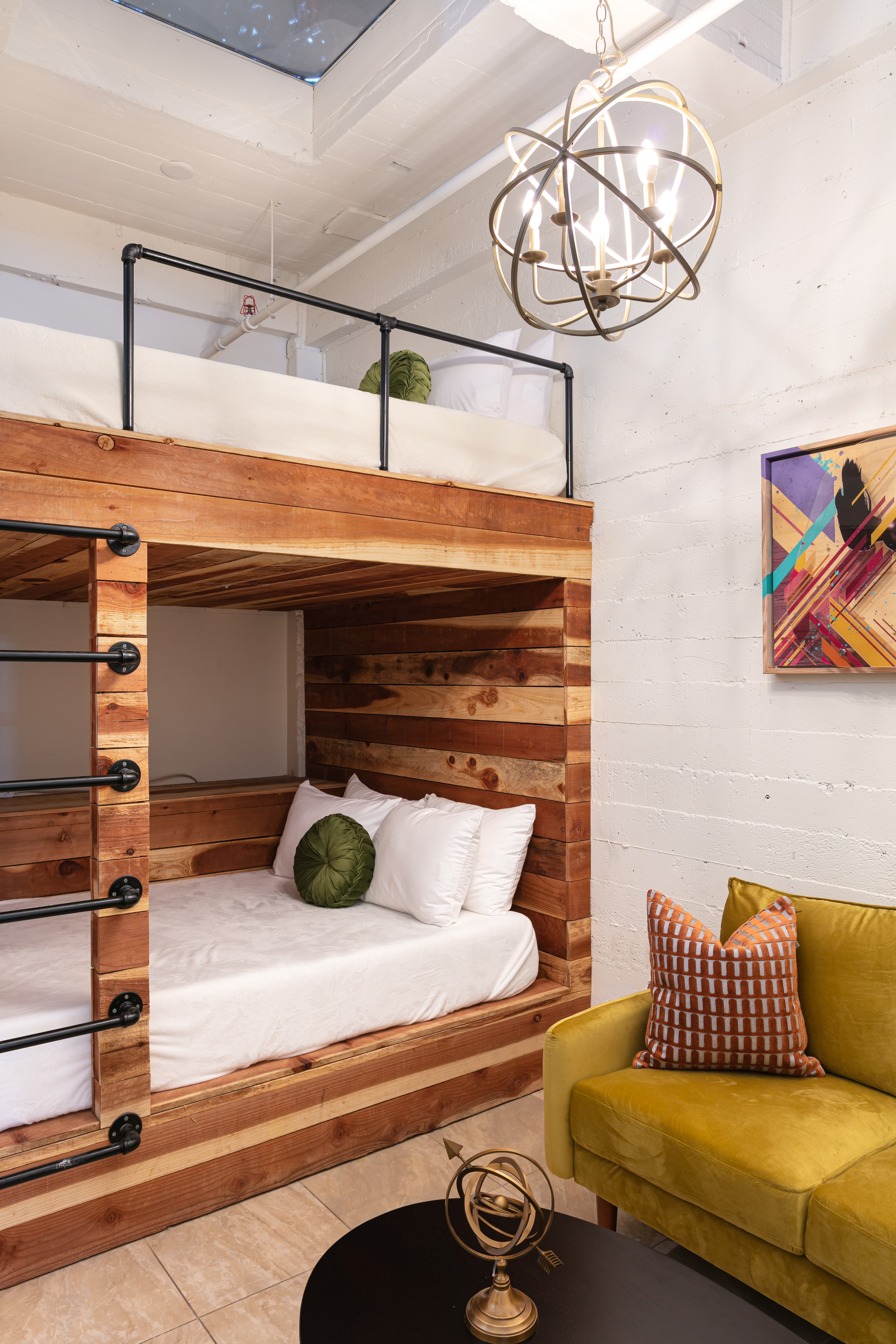 Unit 303 Journeyman — custom wood bunk beds with pipe railings and brass orb chandelier